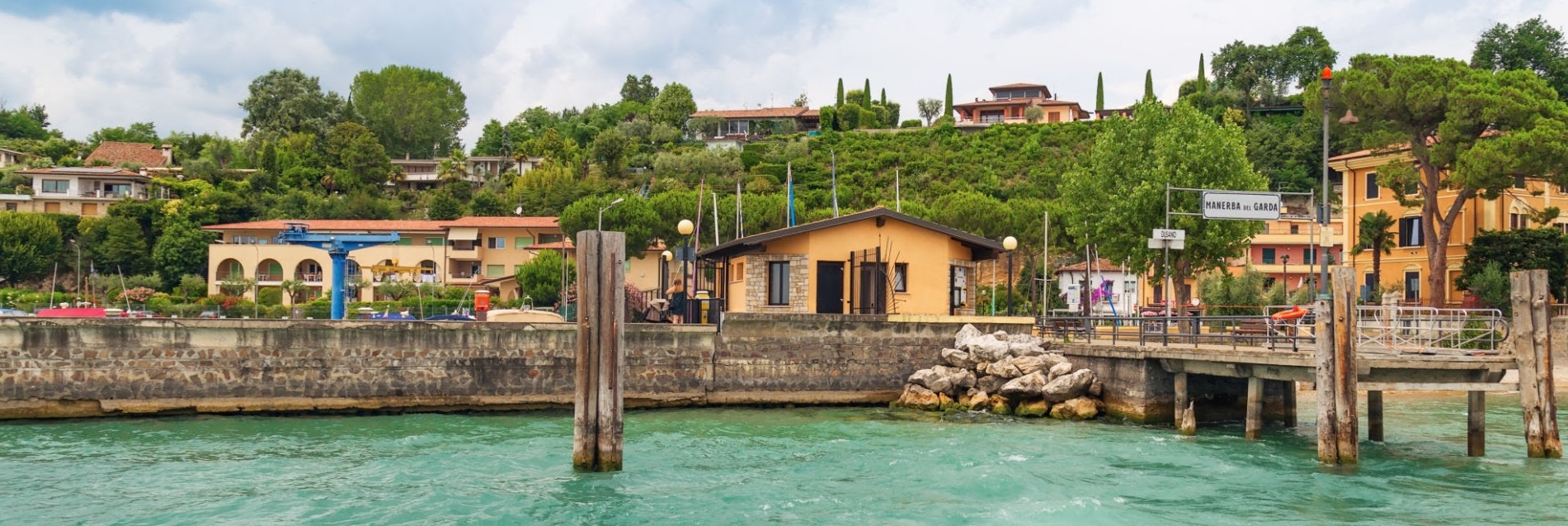 Small wooden pier city of Manerba del Garda is a quiet resort town on the Western shore of lake Garda. The view from the water on small Italian city.